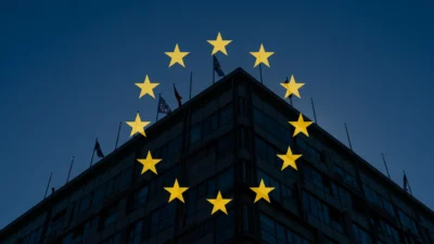 Étoiles européennes en arrière-plan, silhouette de bâtiment officiel, atmosphère réglementaire, tons bleu et or